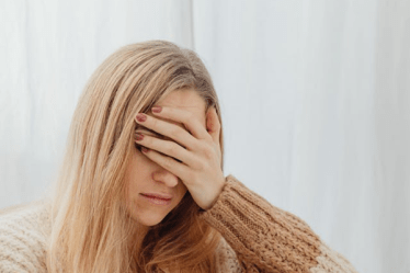 woman with a headache with her hand covering her eyes and forehead